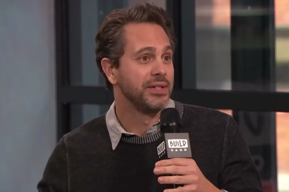 Thomas Sadoski in a dark sweater speaking into a microphone during a BUILD Series interview