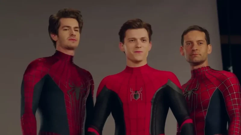 Andrew Garfield, Tom Holland and Tobey Maguire standing side by side in their Spider-Man suits, unmasked, in a photo studio