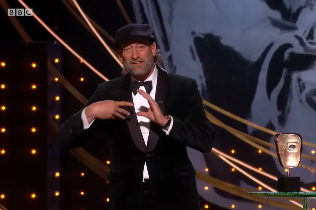Troy Kotsur signing his acceptance speech on stage at the BAFTA Film Awards in London