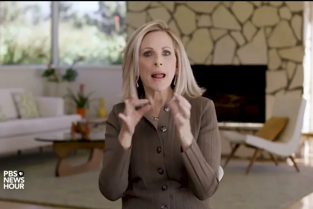 Marlee Matlin signing with both hands raised during a PBS NewsHour interview