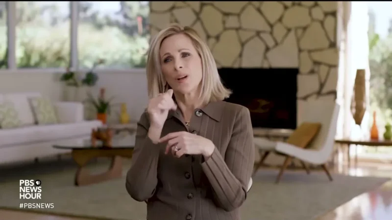 Marlee Matlin signing in American Sign Language in a living room during a PBS NewsHour segment