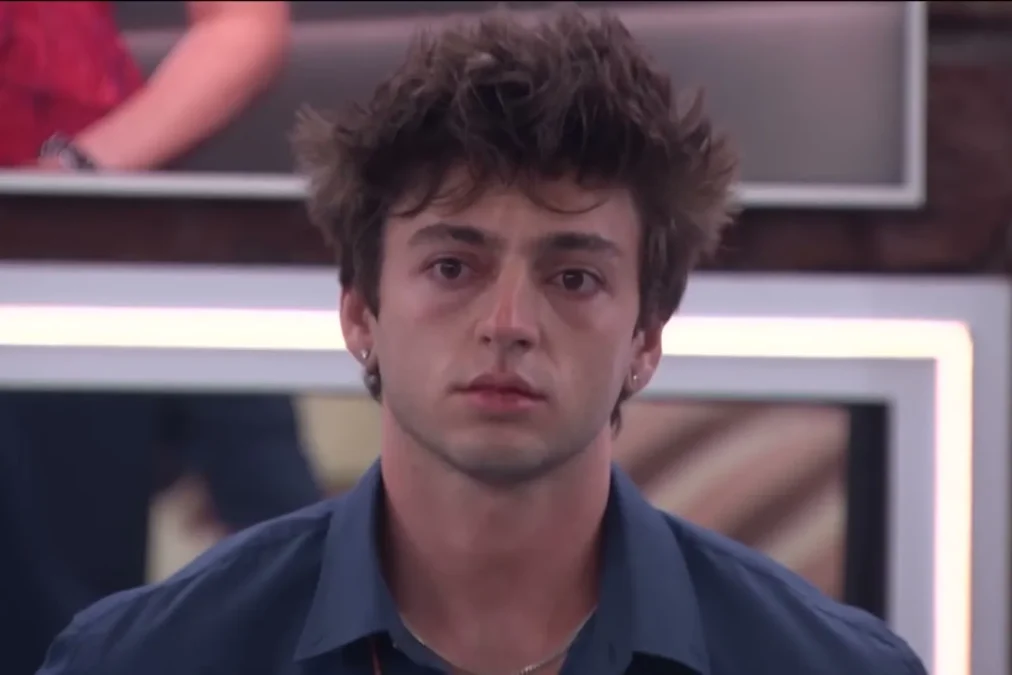 Drew Campbell in a navy shirt with a serious expression in the Big Brother living room