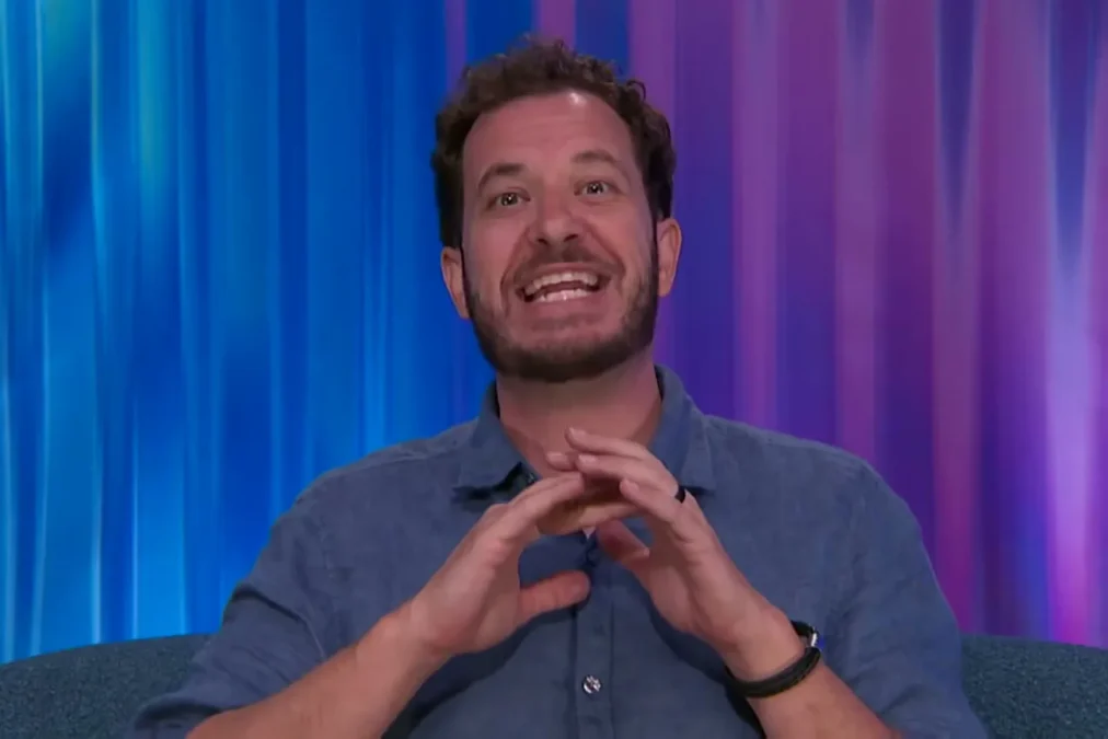 Rick Devens smiling in a blue shirt in the Big Brother Diary Room