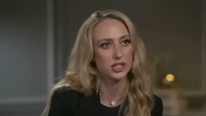 Brittany Mahomes, with long wavy blonde hair and a black top, speaking during a TV interview