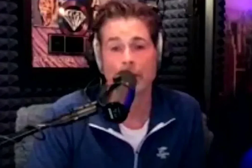 Rob Lowe wearing headphones and speaking into a microphone in a podcast studio