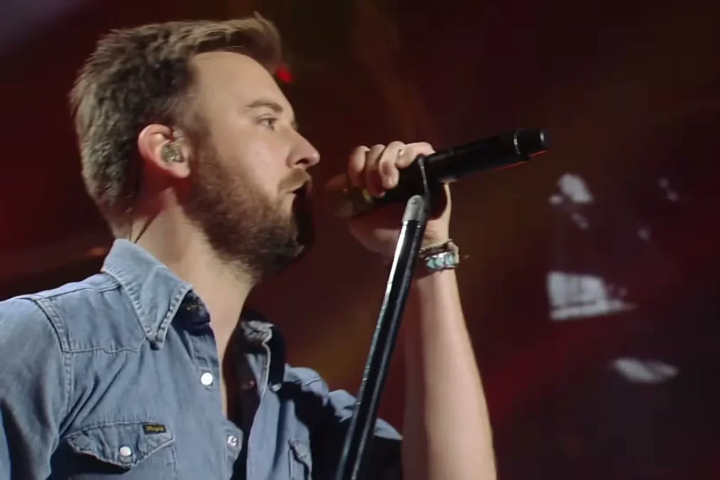 Charles Kelley in a denim shirt singing into a microphone on a stand