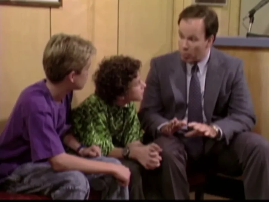 Dennis Haskins as Mr. Belding sitting on a bench beside young Zack Morris and Screech outside the principal's office