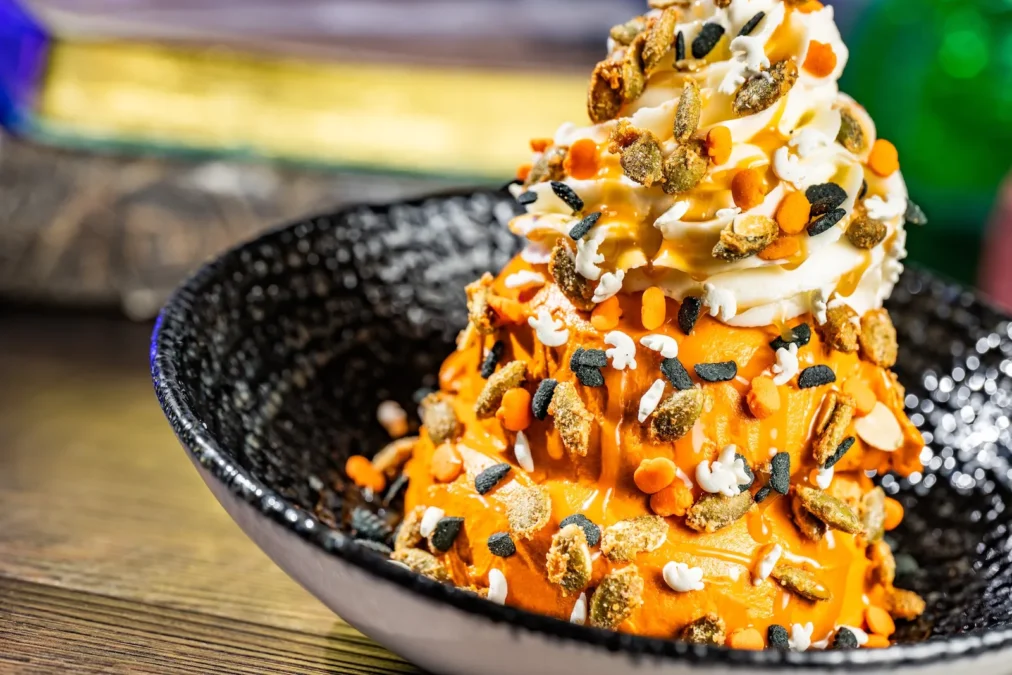 The Pumpkin Sundae at Magic Kingdom's Plaza Ice Cream Parlor: orange pumpkin gelato with caramel sauce, pumpkin brittle and Halloween sprinkles in a black bowl