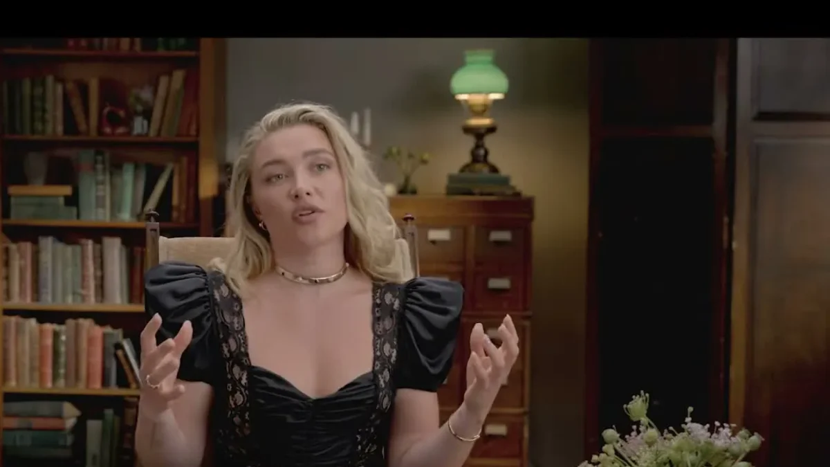 Florence Pugh in a black dress speaking in a library set during a Netflix interview