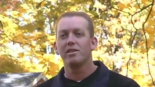 Michigan State turfgrass scientist Kevin Frank speaking outdoors under yellow fall trees