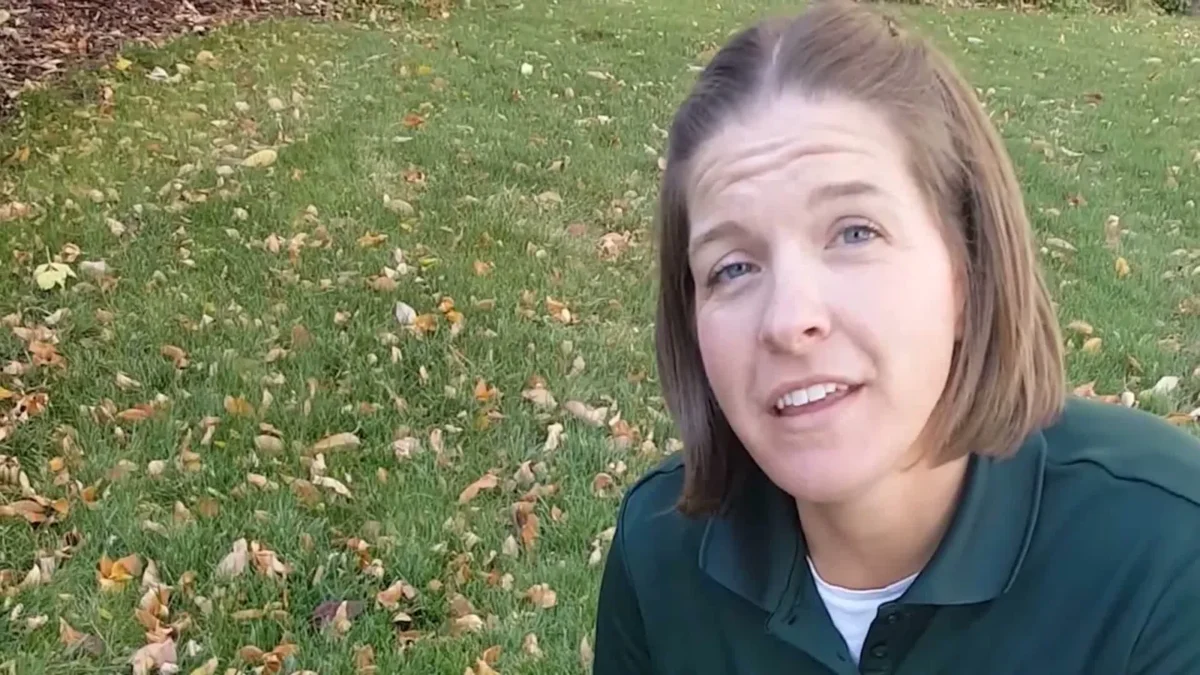 Horticulture agent Alison O'Connor talking to the camera on a green lawn scattered with fallen leaves