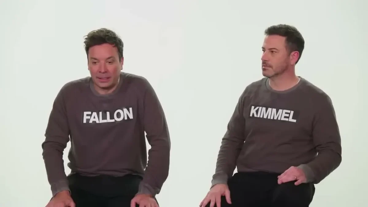 Jimmy Fallon and Jimmy Kimmel sitting side by side in gray sweaters printed with their last names
