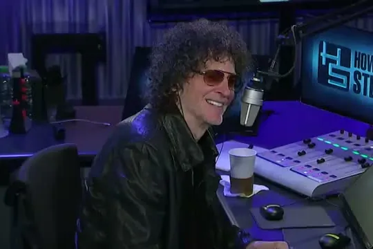 Howard Stern in tinted glasses at the microphone in his radio studio
