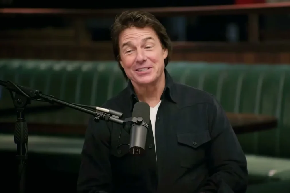Tom Cruise smiling at a microphone on the New Heights podcast set
