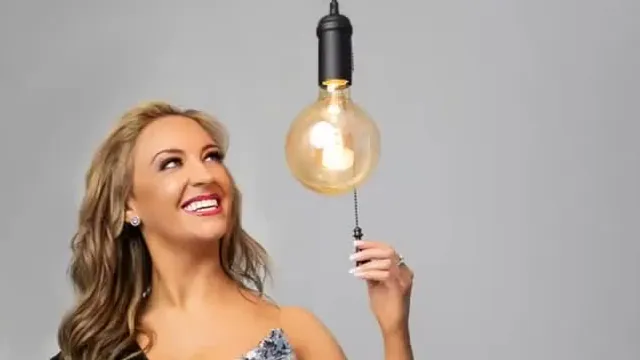 Jennifer Eckhart smiling and looking up at a hanging light bulb in the promotional art for her podcast