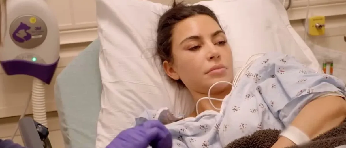 Kim Kardashian lying in a hospital bed in a patient gown in The Kardashians season 8 trailer