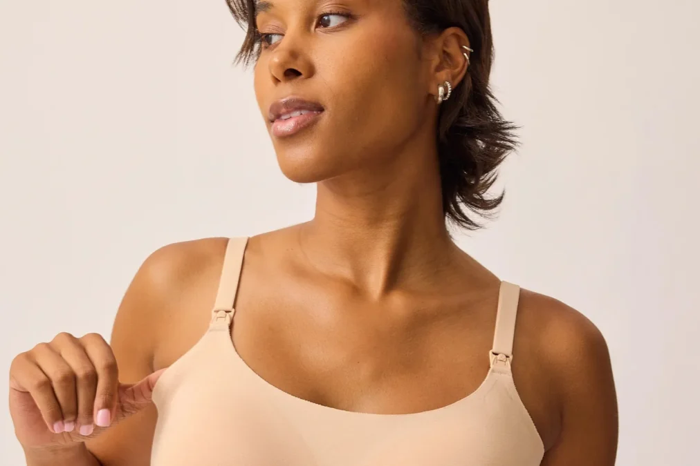 A woman in the sand-colored BareBond pull-on nursing bralette, adjusting a strap