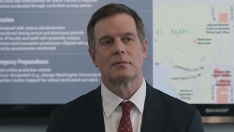 Peter Krause as Secret Service agent Mike Hollingsworth, in a dark suit and red tie, in front of a briefing screen