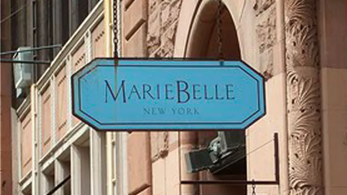 The blue MarieBelle New York sign hanging outside the brand's SoHo flagship on a stone building