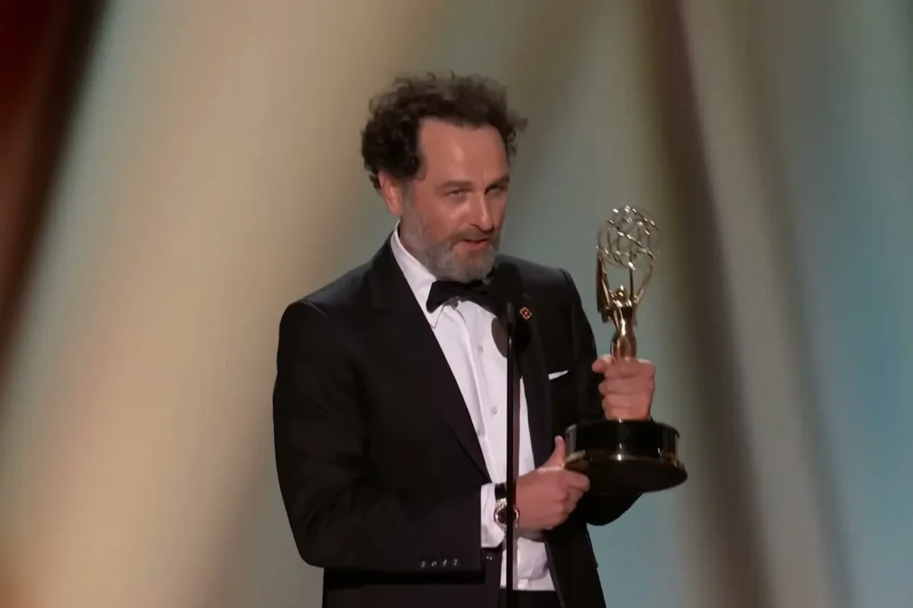 Matthew Rhys holding his Emmy statuette while speaking at the 78th Primetime Emmy Awards