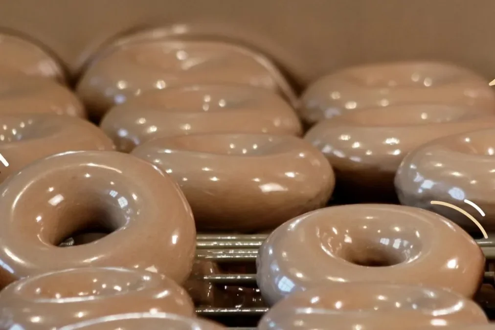 Rows of Krispy Kreme Original Glazed Coffee Flavored Doughnuts with a light brown glaze on a cooling rack