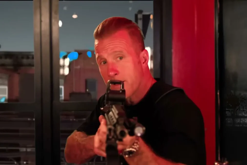 Scott Caan aiming a rifle in a red-lit doorway