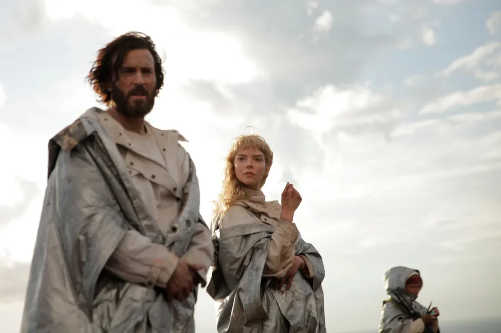 Figures in silver cloaks stand on a hill under a cloudy sky in a scene from Sacrifice