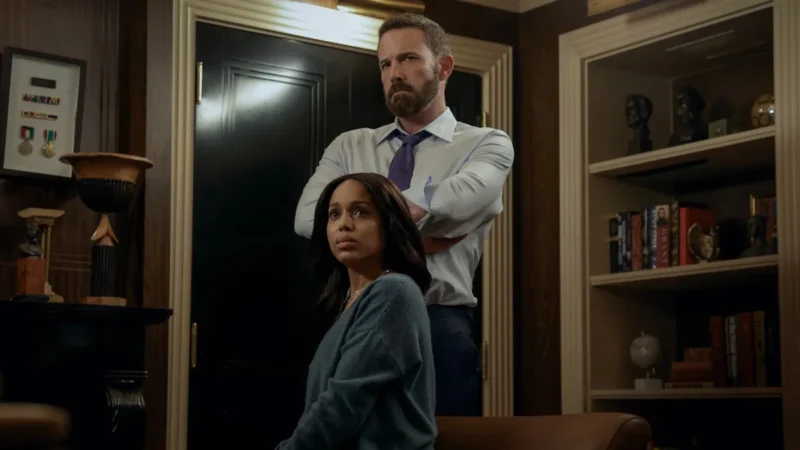 Ben Affleck stands with his arms crossed behind Kerry Washington, who sits in a leather chair looking worried, in a dim office in Animals
