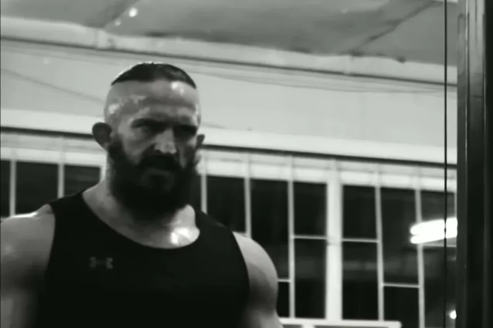 Black-and-white image of PAC in a black tank top in a gym