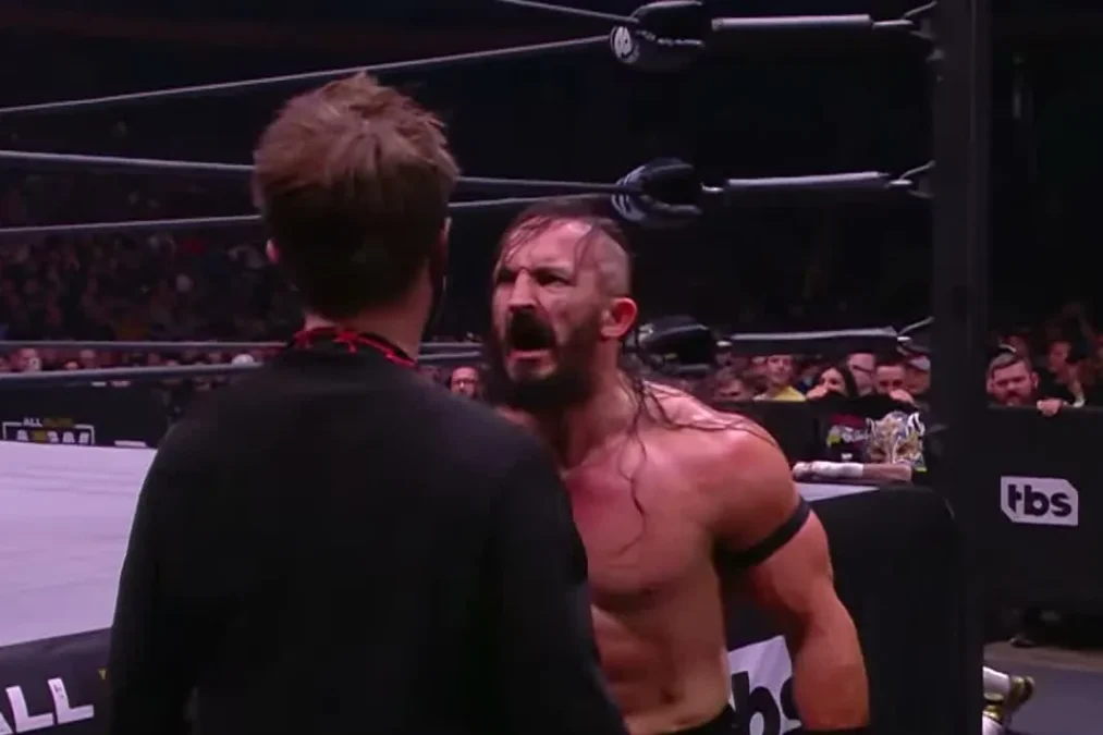 PAC shouting at a man in a black jacket at ringside during AEW Dynamite
