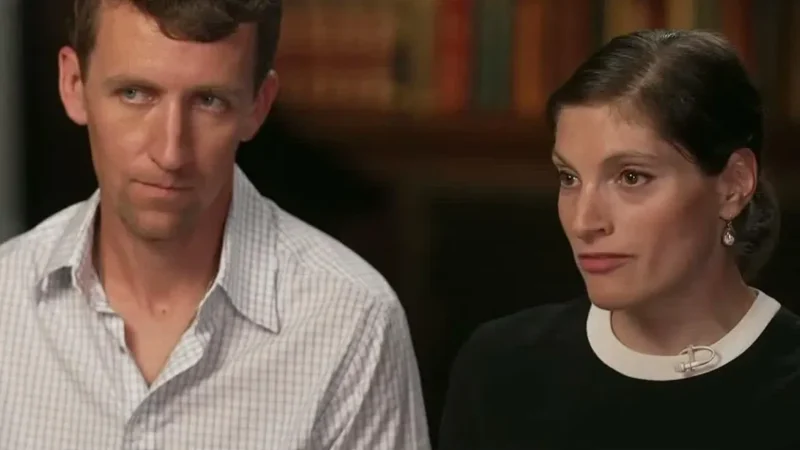 Patrick Clancy in a checked shirt sitting beside his wife, Dr. Rachel Danis, during their 60 Minutes interview