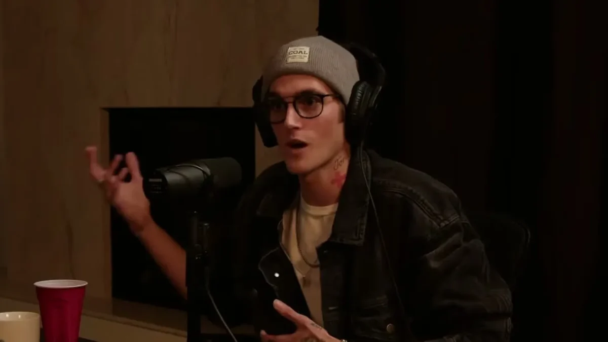 Presley Gerber in glasses and a gray beanie, mid-sentence during a podcast interview