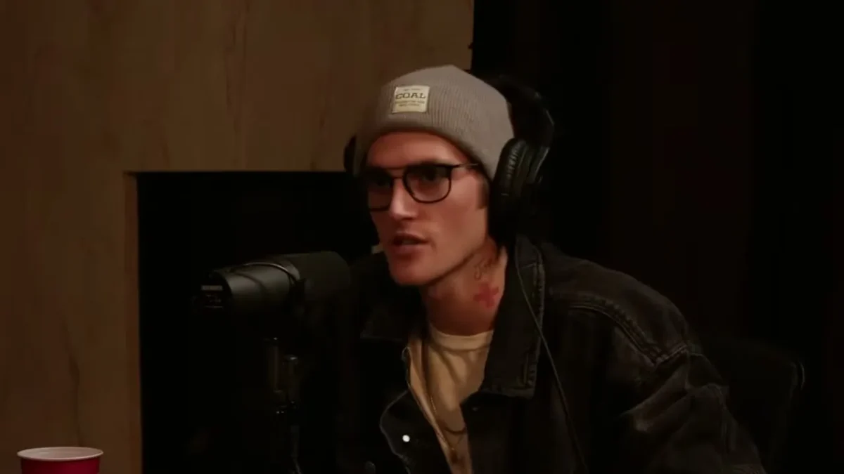 Presley Gerber in glasses, a gray beanie and headphones, speaking into a microphone on the Studio 22 podcast