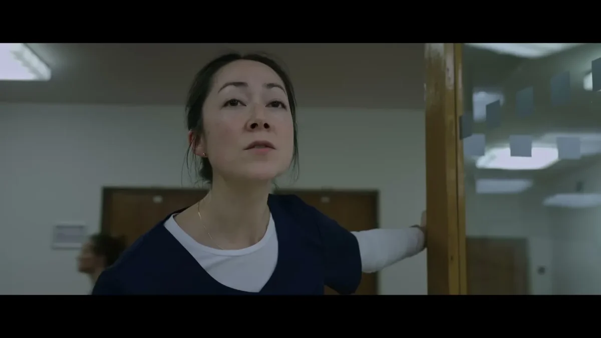 A woman in a hospital corridor looks toward the camera in a scene from Resident Evil (2026)
