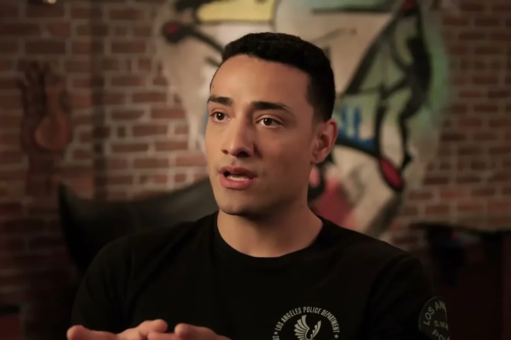 Freddy Miyares in a black T-shirt talking with his hands clasped in an interview