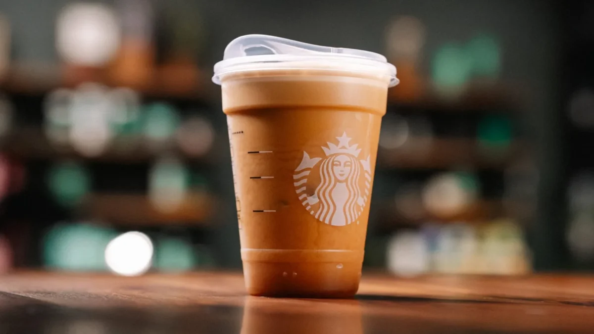 The Starbucks Aerocano in a clear to-go cup with a lid on a wooden counter, a pale foam layer at the top of the iced espresso drink