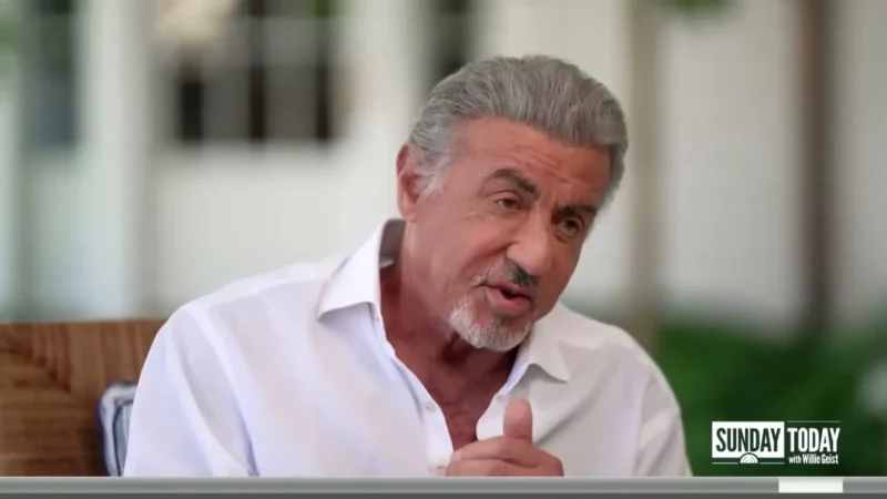Sylvester Stallone in a white shirt gesturing during a TODAY interview on a porch