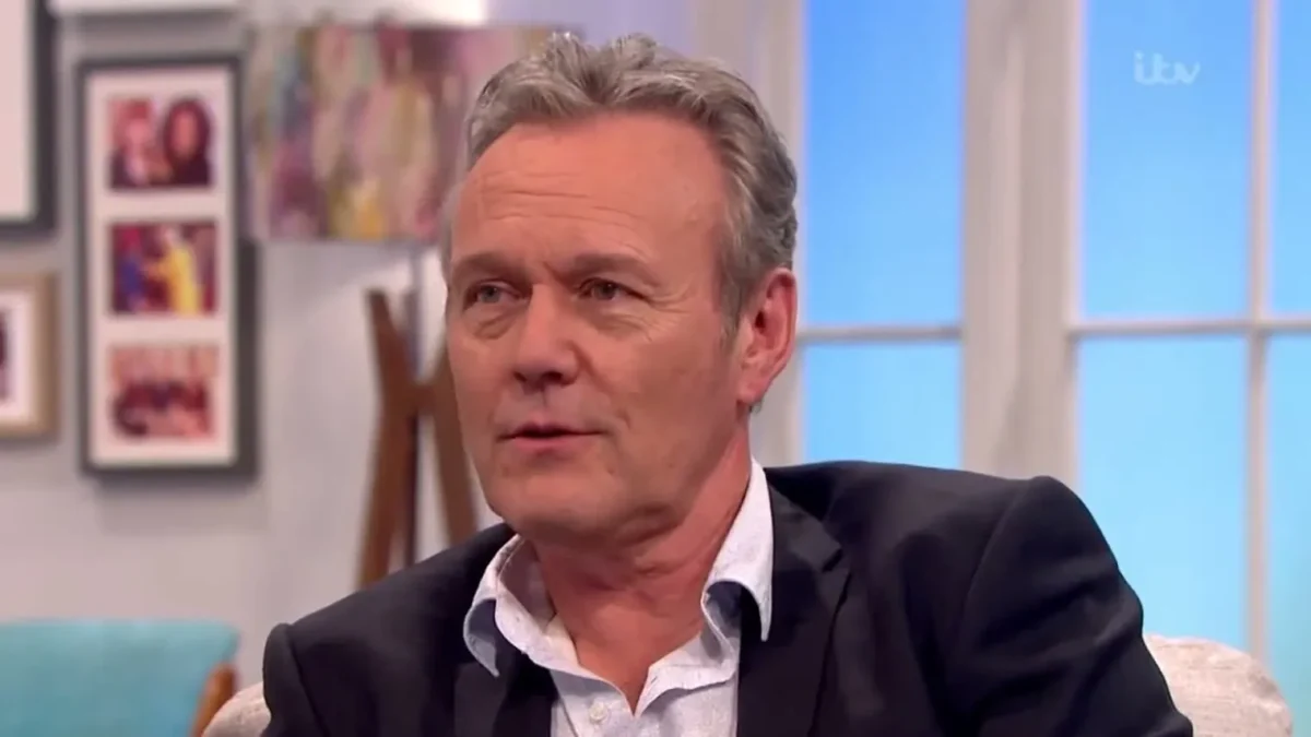 Anthony Head in a dark jacket and open white shirt on the Lorraine sofa