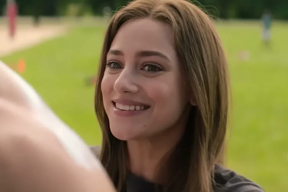 Lili Reinhart as Olive smiling in a park in a scene from The Love Hypothesis