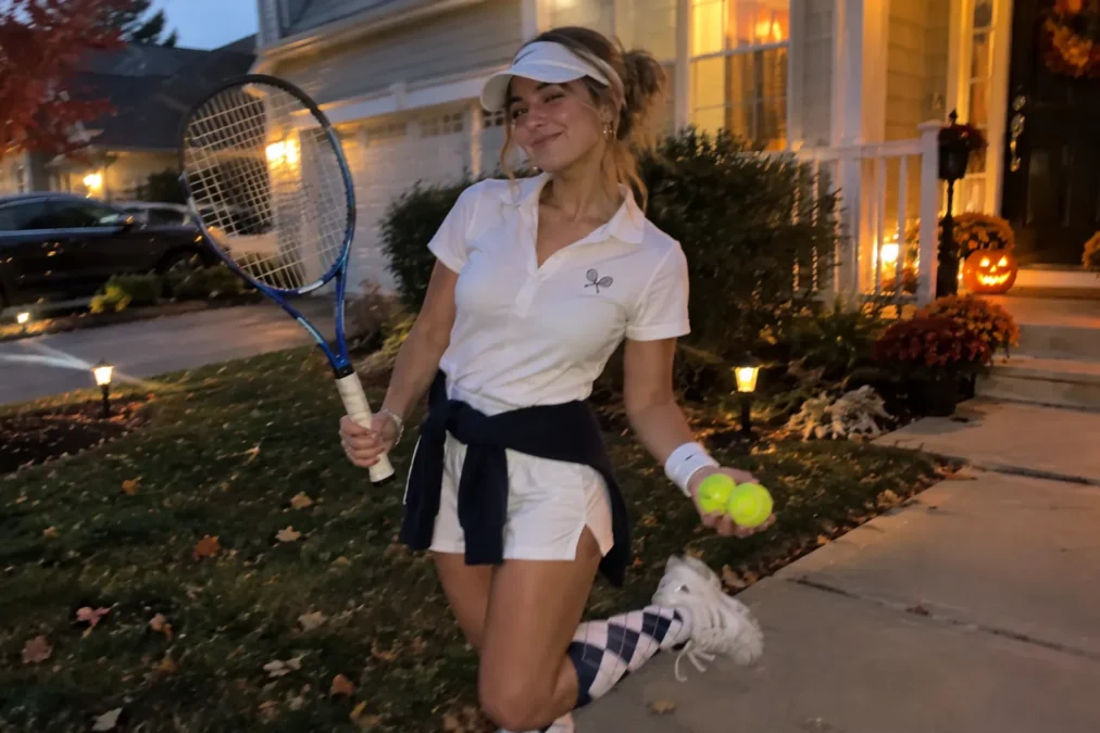 Illustration of a woman dressed as a tennis player in a white polo, visor, sweater tied at the waist and argyle socks, holding a racket and tennis balls