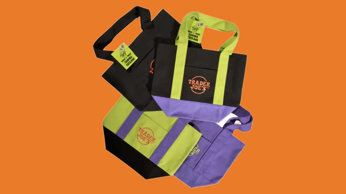 Four Trader Joe's Trick-or-Treat mini canvas totes in black, purple, lime green and black with lime green handles, on an orange background