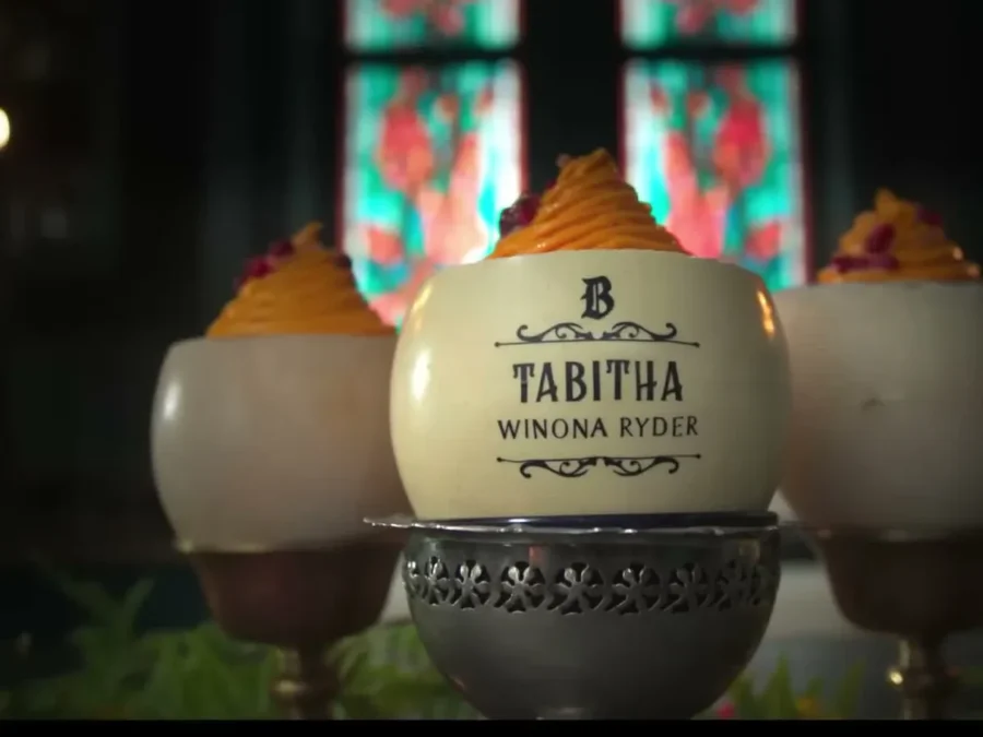 A decorated egg with a place card reading Tabitha, Winona Ryder, between two frosted desserts