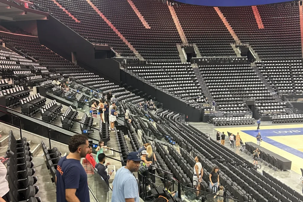 Fans walking through the lower bowl of Intuit Dome to pick seats, with the LA VB logo on the arena's halo screen
