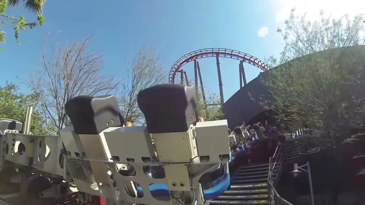 The X2 roller coaster's winged seats, seen from the front of the train, with the ride's red track looping against a blue sky at Six Flags Magic Mountain