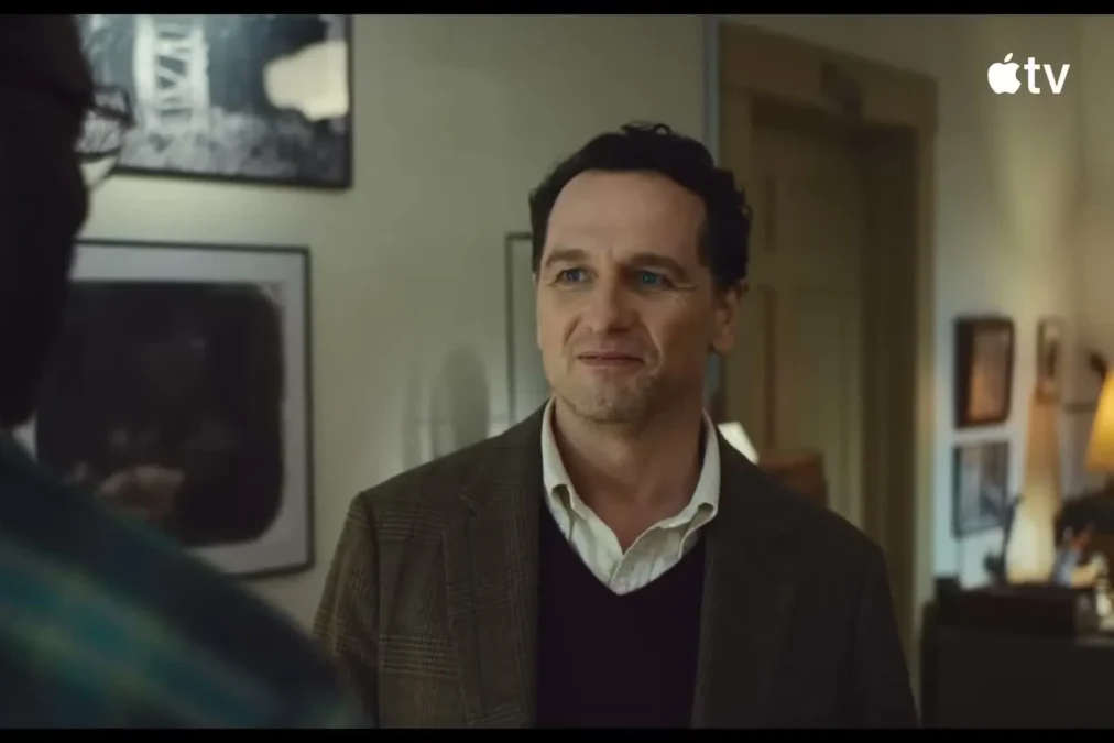 Matthew Rhys as Tom Loftis standing in a wood-panelled office in Widow's Bay