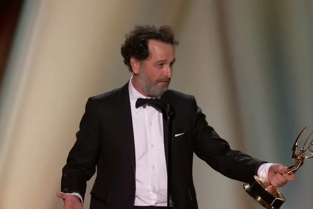 Matthew Rhys holding his Emmy statuette and gesturing during his acceptance speech