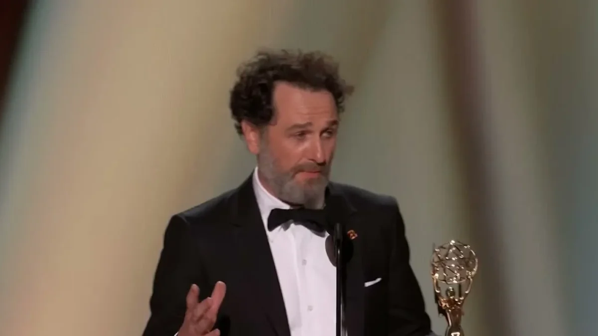 Matthew Rhys in a tuxedo holding his Emmy statuette at the podium of the 78th Primetime Emmy Awards