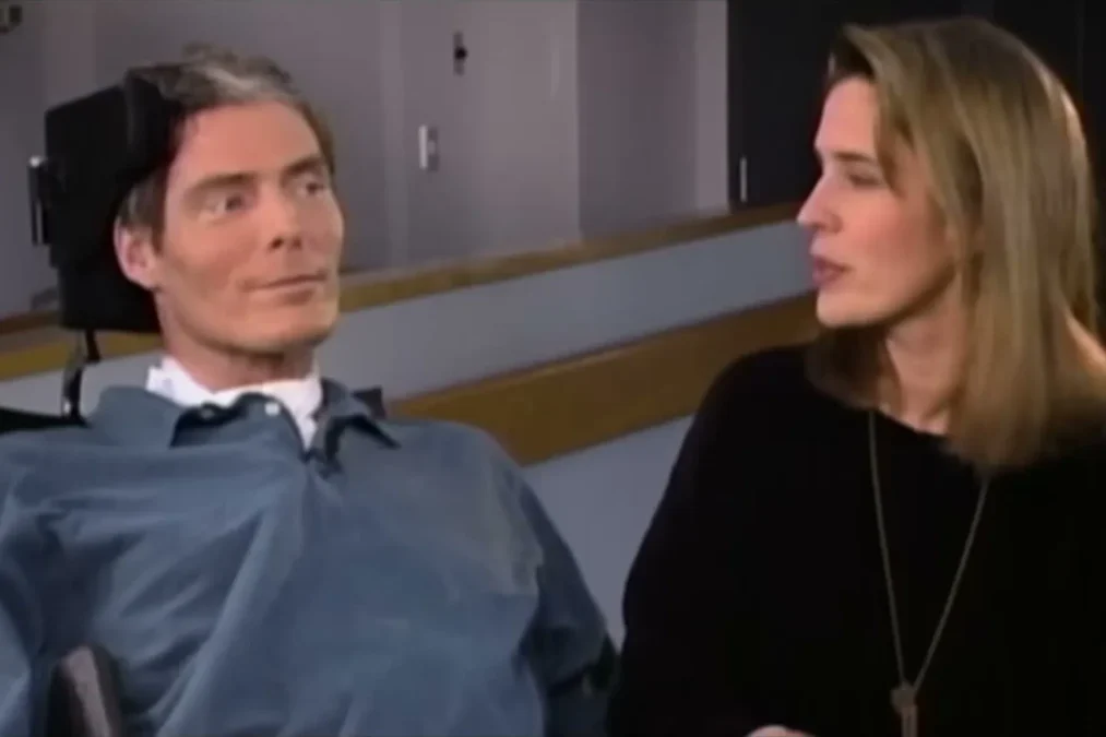 Christopher Reeve in a wheelchair beside Dana Reeve, who is turned toward him, in archival footage