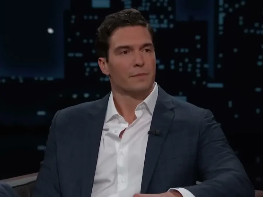 Will Reeve in a navy blazer and open white shirt, sitting as a guest on Jimmy Kimmel Live