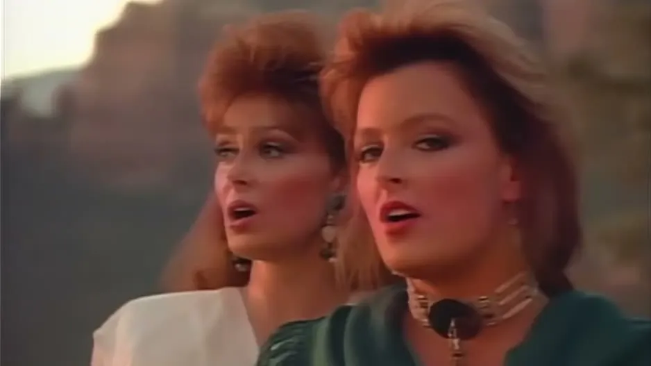 Naomi Judd and Wynonna Judd singing outdoors with red rocks behind them in the Love Can Build a Bridge video